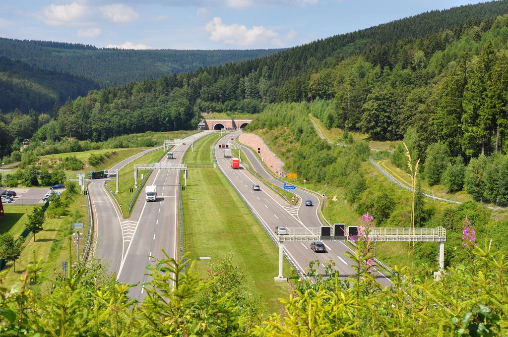 rechte und linke Autobahnspuren der A71 Richtung Eingang des Rennsteigtunnels, getrennt durch breiten Grünstreifen