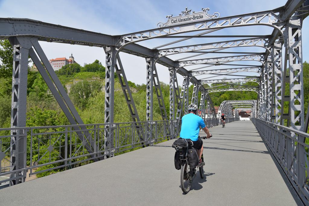Ein Radfahrer auf dem Radweg fährt über eine Metallbrücke.