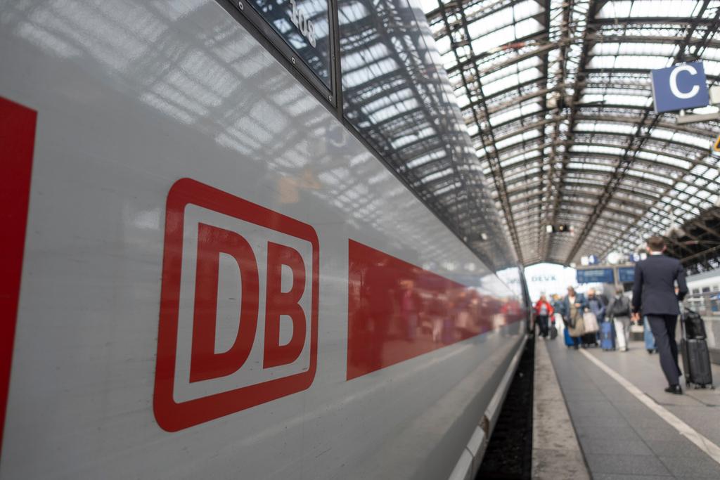 ICE mit dem Logo der Deutschen Bahn am Bahnsteig mit Fahrgästen im Bahnhof