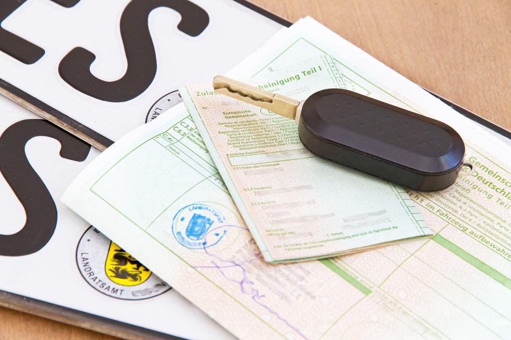Autopapiere, Autoschlüssel und Kennzeichen liegen auf einem Tisch