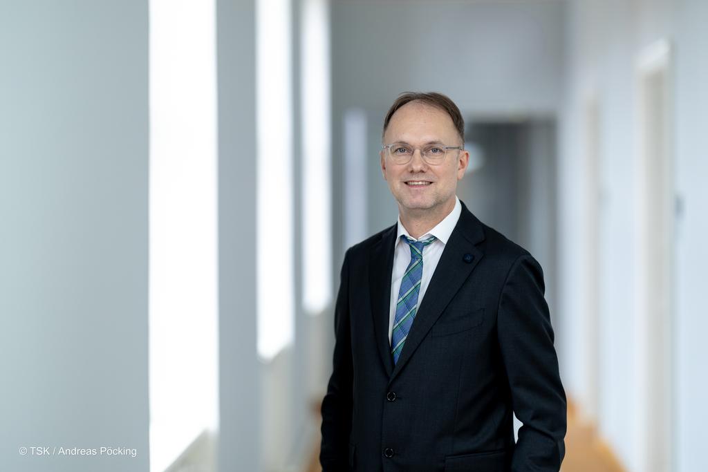 Staatssekretär Dr. Tobias J. Knoblich steht vor dem Gebäude des TMDI