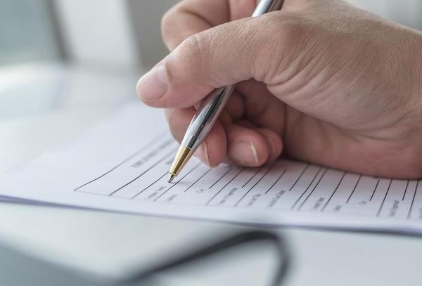 Applicant filling in company application form document applying for job, or registering claim for health insurance