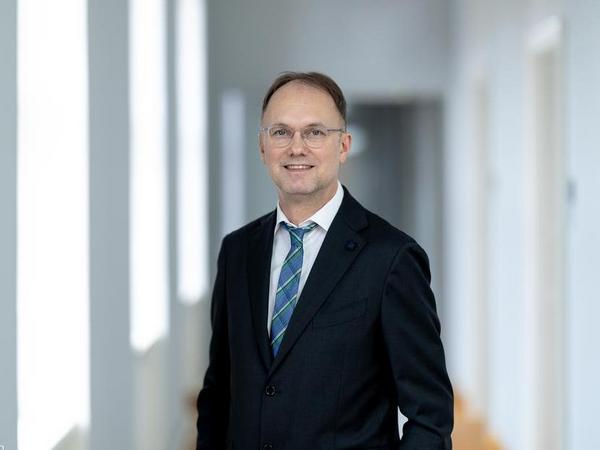 Staatssekretär Dr. Tobias J. Knoblich steht vor dem Gebäude des TMDI