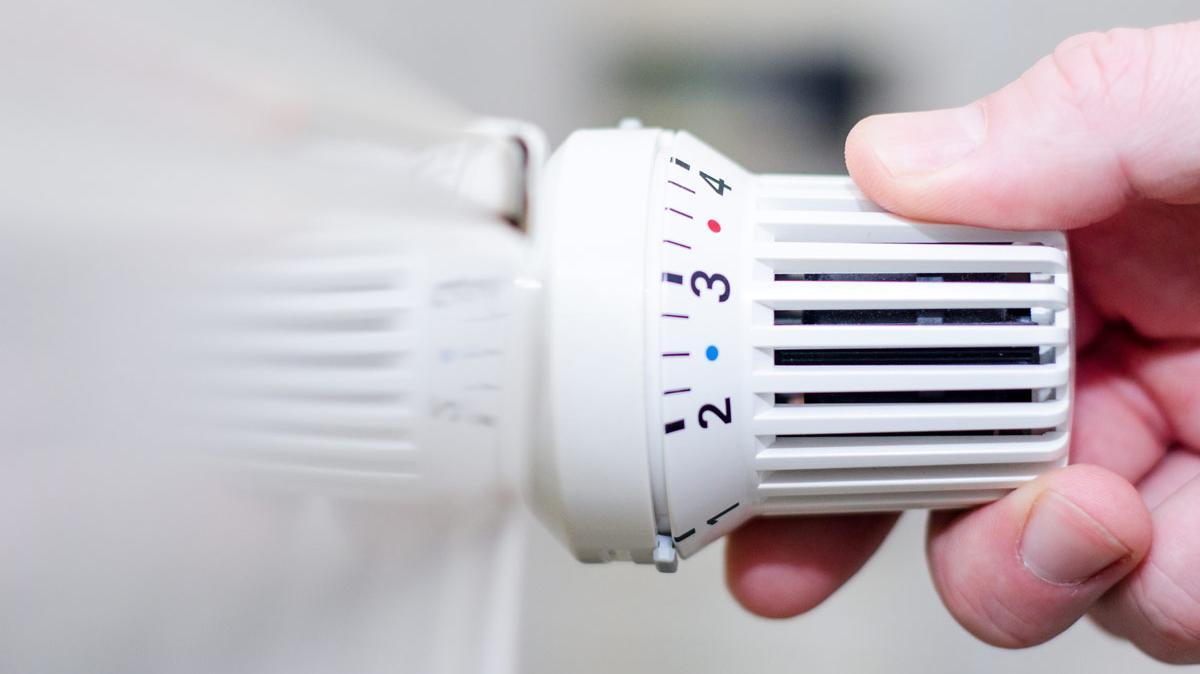 Closeup Hand dreht an Heizungsthermostat