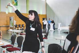 Eine Kollegin des TMIL läutet die Glocke zum Ende der Speed-Dating-Runde