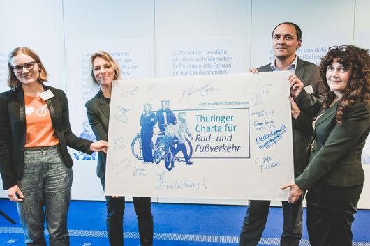Frieda Nagler (ADFC Thüringen, Vorsitzende), Ministerin Susanna Karawanskij, Christian Gerlitz und Petra Enders (beide AGFK Thüringen) halten die Tafel mit den Unterschriften