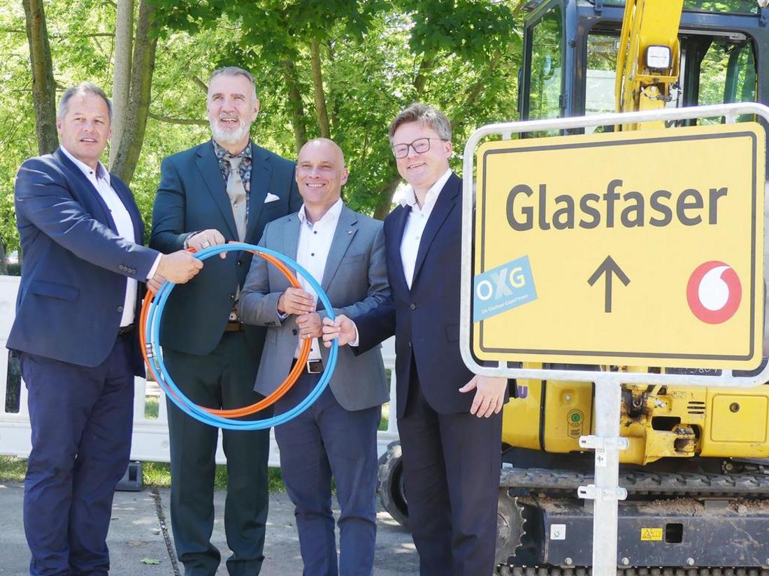 Minister Steffen Schütz, Oberbürgermeister und Herren der OXG stehen vor einem Schild mit der Aufschrift Glasfaser und halten zwei Kabel in ihren Händen