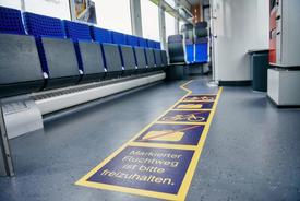 Fahrgastinnenraum der Bahn mit rechts und links je 2 blauen Sitzplätzen.