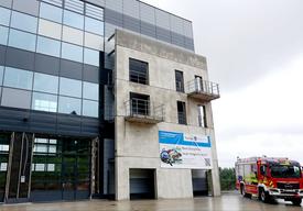 Fahrzeughalle mit Feuerwehrauto. Ein Banner mit Hinweis auf die Eröffnung hängt an der Fassade.