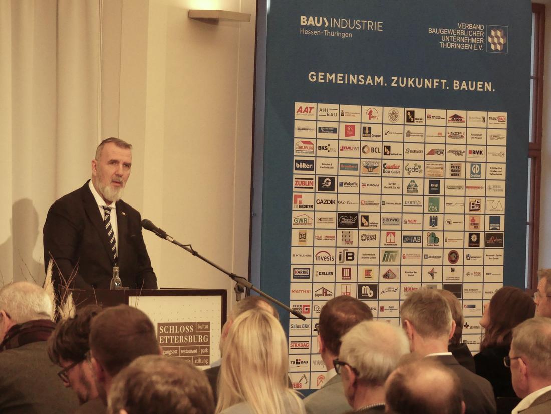 Bauminister Steffen Schütz hält zur Jahresauftaktveranstaltung der Bauwirtschaft eine Rede. Er steht an einem Pult vor sitzenden Personen und spricht.