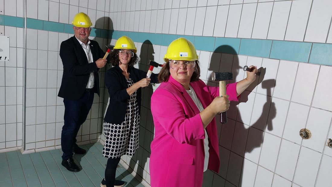 Staatssekretärin Prof. Schönig beim Sanierungsbeginn der Schwimmhalle in Greiz klopft symbolisch Fliesen von einer Wand
