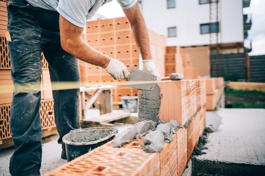 Ein Bauarbeiter mauert eine Mauer aus Ziegelsteinen
