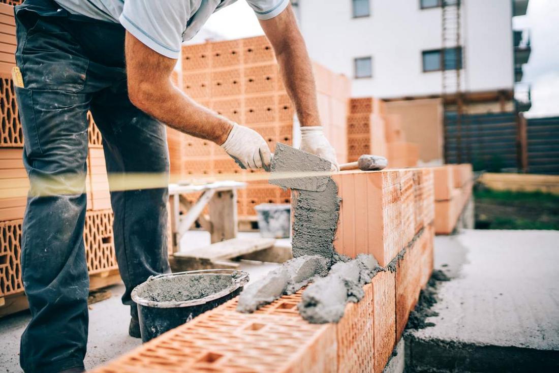 Ein Bauarbeiter mauert eine Mauer aus Ziegelsteinen
