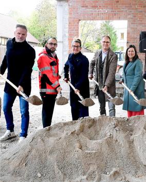 Vier Personen und der Staatssekretär Dr. Tobias Knoblich stehen mit Schaufeln vor einem großen Sandhaufen anlässlich der Grundsteinlegung der Mensa der Evangelischen Regelschule Gotha