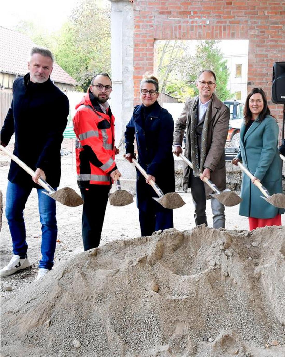 Vier Personen und der Staatssekretär Dr. Tobias Knoblich stehen mit Schaufeln vor einem großen Sandhaufen anlässlich der Grundsteinlegung der Mensa der Evangelischen Regelschule Gotha