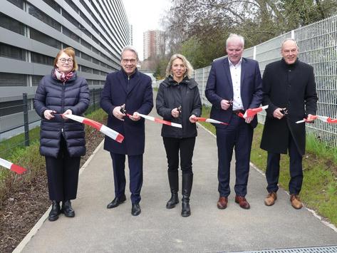 Symbolische Eröffnugn eines neuen Radweges. Fünf Personen haben ein Absperrband durchschnitten und schauen in die Kamera.