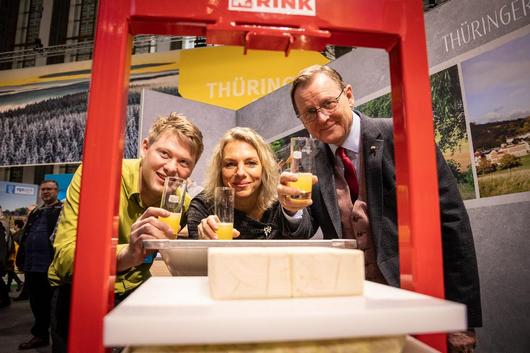 Maik Rahaus (Wunsch-Saft-Kelterei), Ministerin Susanna Karawanskij und Ministerpräsident Bodo Ramelow mit frisch gepresstem Apfelsaft an einer Saftpresse