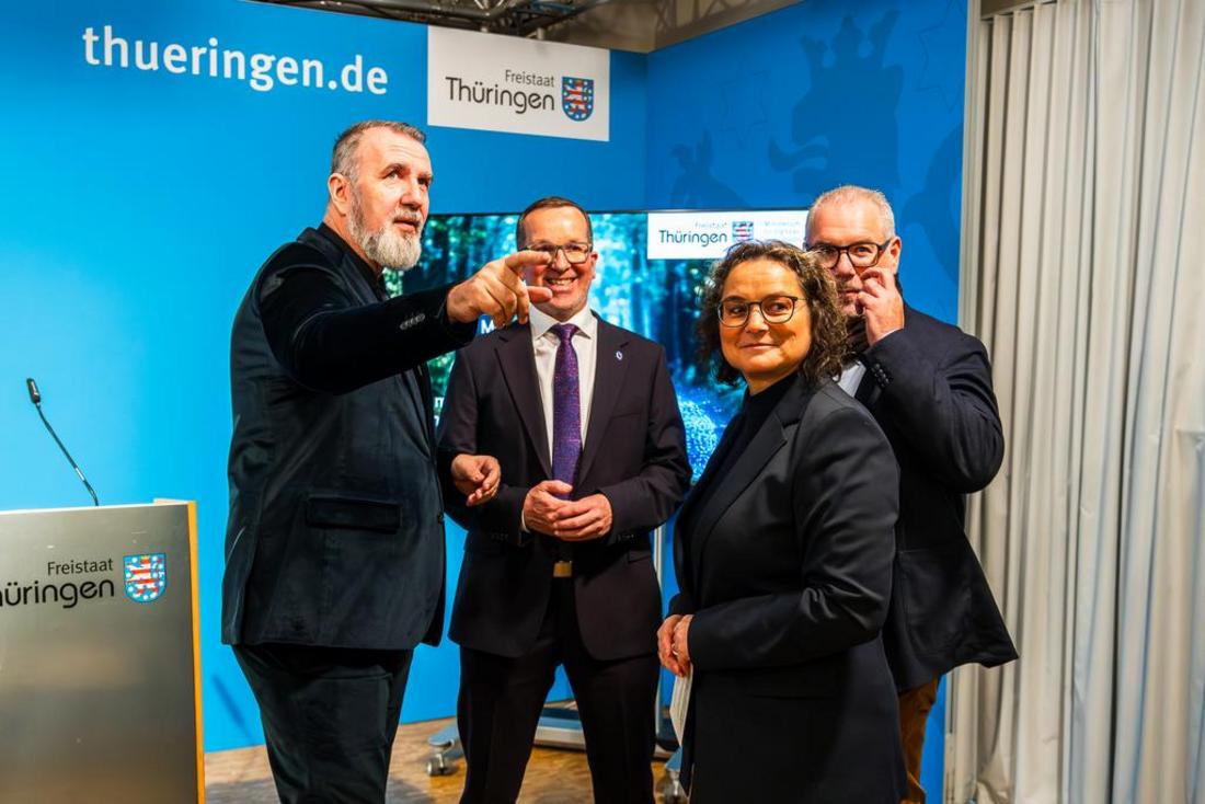 Minister Steffen Schütz steht gemeinsam mit drei Personen vor einem Bildschirm und präsentiert das Baupaket 2025