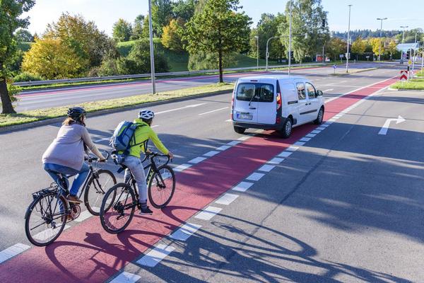 Zwei Radfahrer fahren mit dem Fahrrad auf roten Fahrradstreifen einer Straße