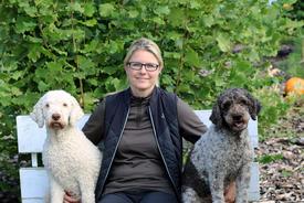 Unternehmerin Anja Kolbe-Nelde sitzt auf einer Bank. Rechts und links neben ihr jeweils ein Hund.