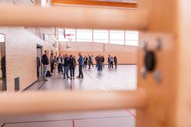 Blick durch eine Sprossenwand auf Personen in der Sporthalle