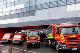Vier Feuerwehrfahrzeuge stehen aufgereiht vor der neuen Ausbildungs- und Fahrzeughalle.