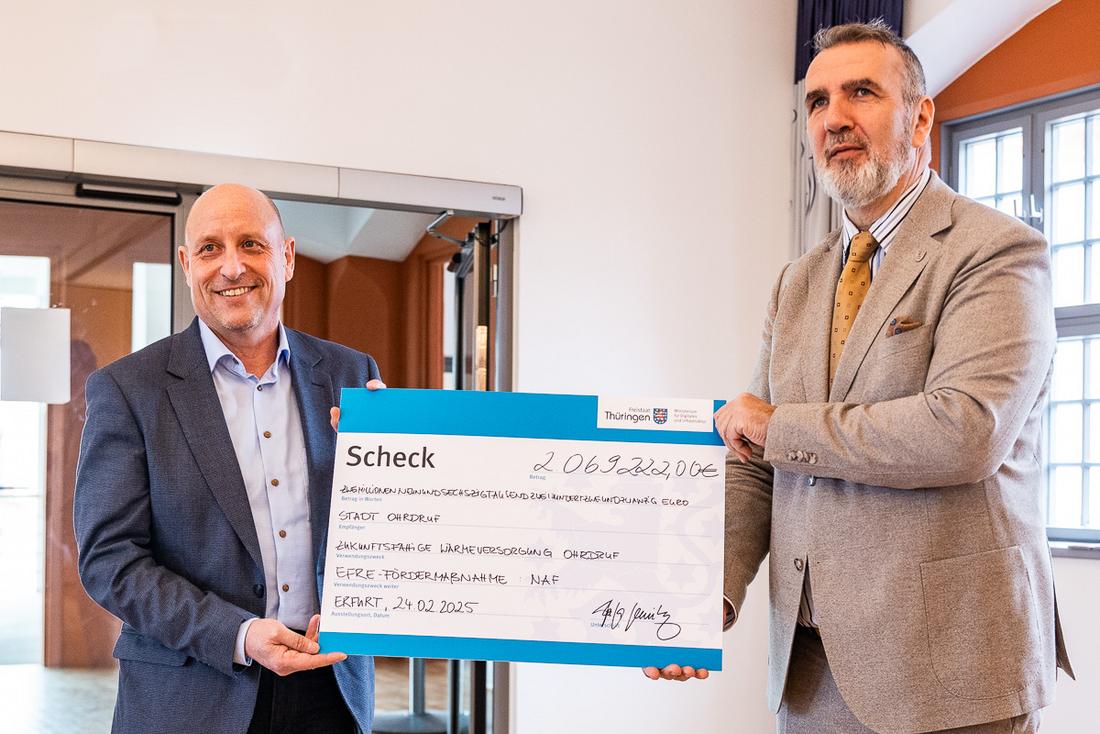 Ohrdrufs Bürgermeister Stefan Schambach (links) und Infrastrukturminister Steffen Schütz halten einen symbolischen Scheck