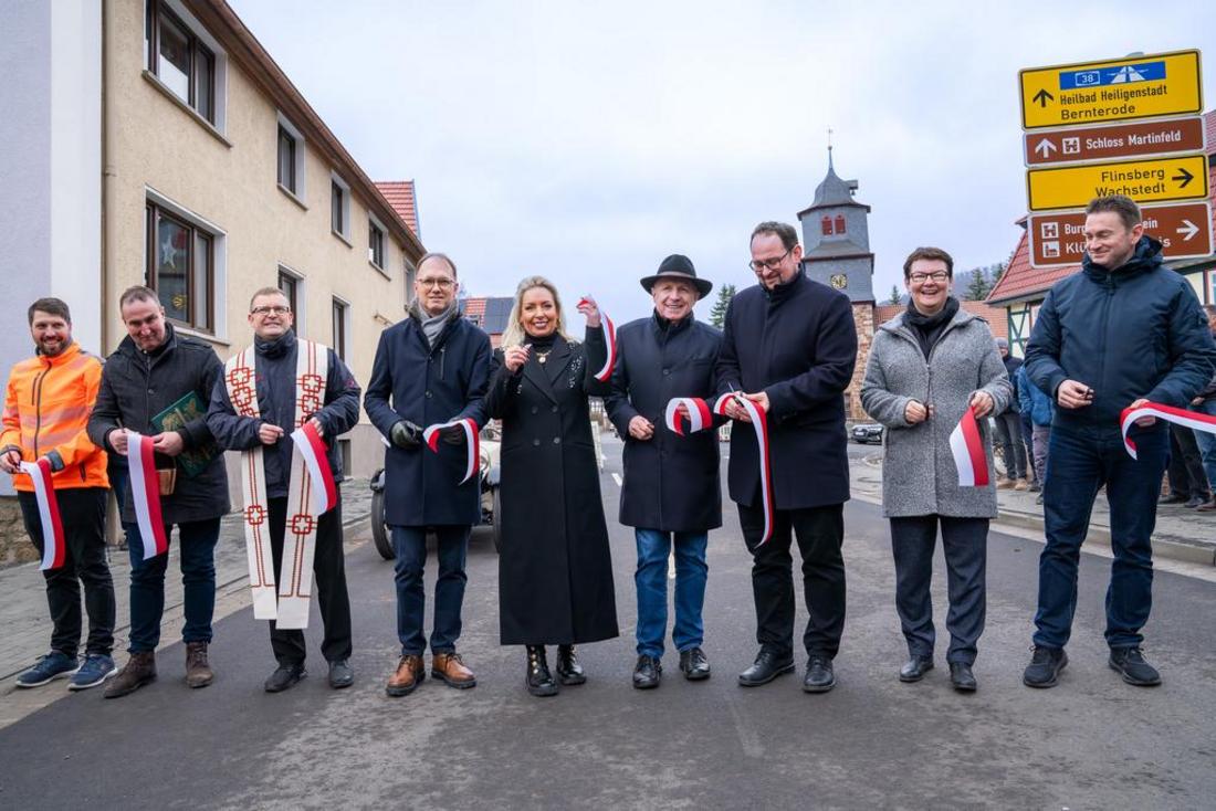 Staatssekretär Dr. Tobias Knoblich und weitere Leute stehen an einem rotweißen Band auf der neuen Landstraße L1007 und freuen sich diese symbolisch zu eröffnen
