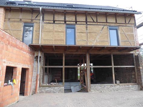 Ein Haus, das gerade renoviert wird, mit freiliegendem Holzgerüst und Baumaterialien.