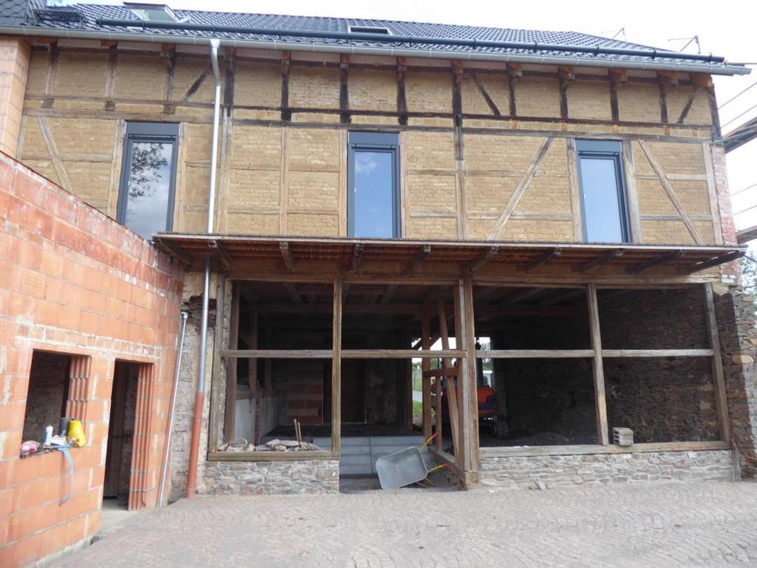 Ein Haus, das gerade renoviert wird, mit freiliegendem Holzgerüst und Baumaterialien.
