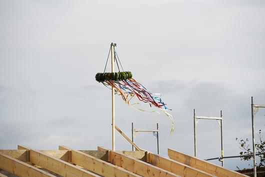 Geschmückter Richtkranz auf Dachstuhl wehend im Wind