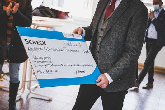 Bad Salzungens Bürgermeister Klaus Bohl hält den symbolischen Scheck über 2,025 Millionen Euro