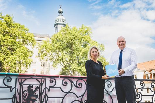 Ministerin Susanna Karawanskij übergibt einen Bescheid an Bürgermeister Steffen Grimm auf dem Balkon des Sondershäuser Rathauses