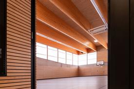 Blick in die neue Sporthalle, viel Holz an Decke und Wänden und große Fenster